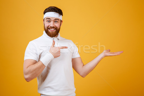 Stock photo: Pleased sportsman pointing at the invisible copyspace on pound