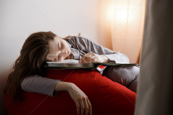 Vertical image of woman sleeping on bag chair with book Stock photo © deandrobot