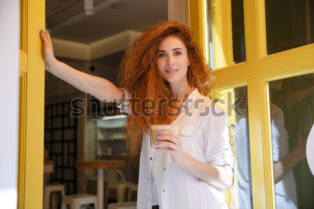 Cute redhead woman with long hair holding cup of coffee Stock photo © deandrobot