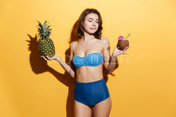Pretty young girl in beachwear holding coconut drink and pineapple Stock photo © deandrobot