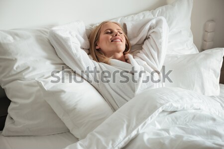 Young happy woman lying on big white bed Stock photo © deandrobot