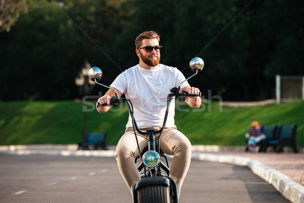 Smiling bearded man in sunglasses rides on modern motorbike Stock photo © deandrobot
