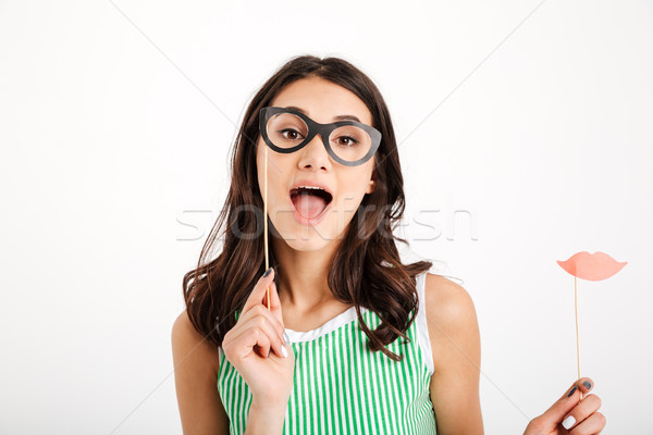 Portrait of a cheery girl holding paper eyeglasses Stock photo © deandrobot