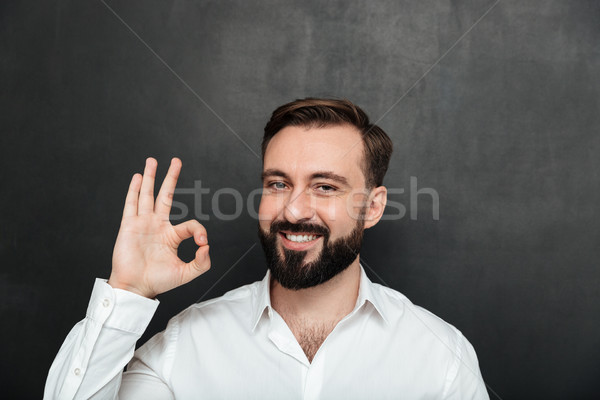 Close up photo of bearded guy smiling and gesturing with OK sign Stock photo © deandrobot