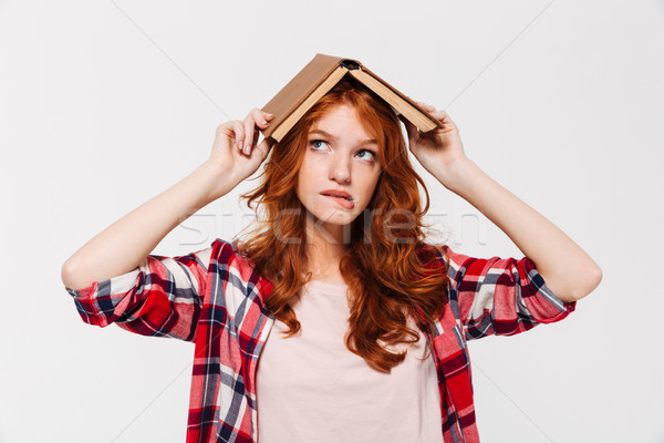 Ginger woman in shirt holding book on head like roof Stock photo © deandrobot