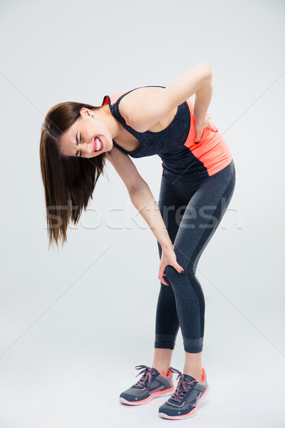 Sportos nő hátfájás teljes alakos portré szürke Stock fotó © deandrobot