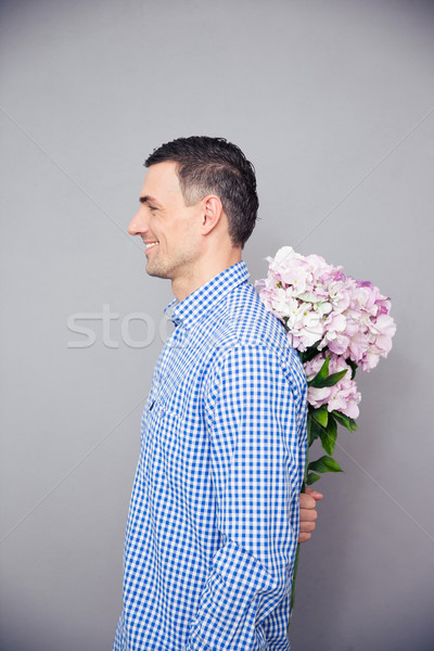 Happy man hiding flower behind his back Stock photo © deandrobot