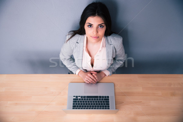 Yuong businesswoman sitting at the table with latpop Stock photo © deandrobot