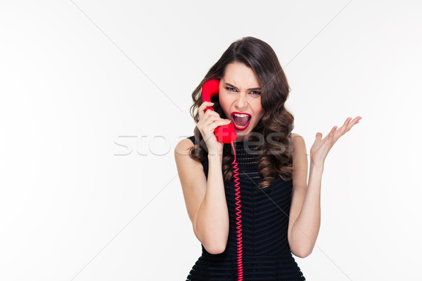 Hysterical aggressive young female shouting and talking on red telephone  Stock photo © deandrobot