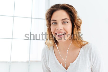 Happy thoughtful woman with earphones Stock photo © deandrobot