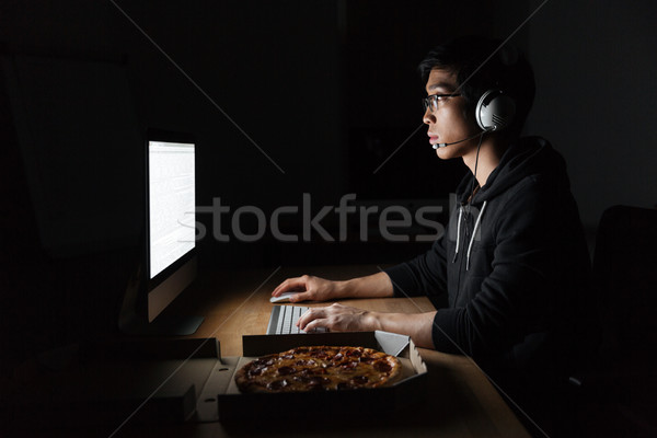 Man working with computer and eating pizza in dark room Stock photo © deandrobot