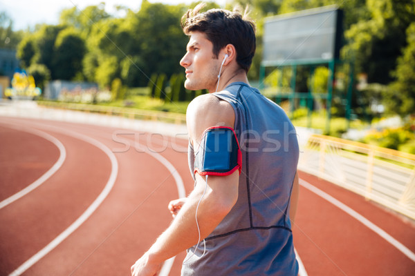 Back view of a runner listening music with mobile phone Stock photo © deandrobot