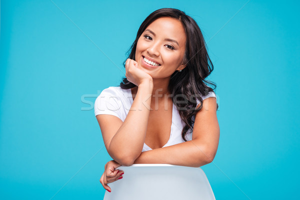 Cheerful young vietnamese woman sitting on the chair Stock photo © deandrobot