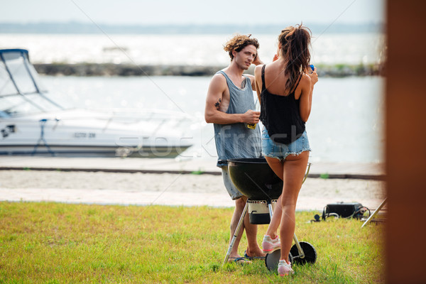 Couple standing and frying meet on barbeque grill outdoors Stock photo © deandrobot