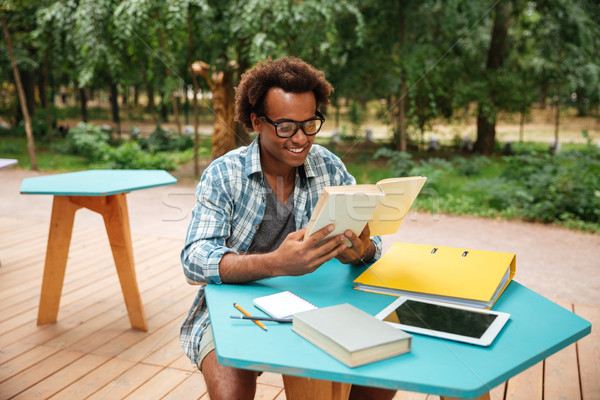 Happy handsome young man reading and sudying in outdoor cafe Stock photo © deandrobot