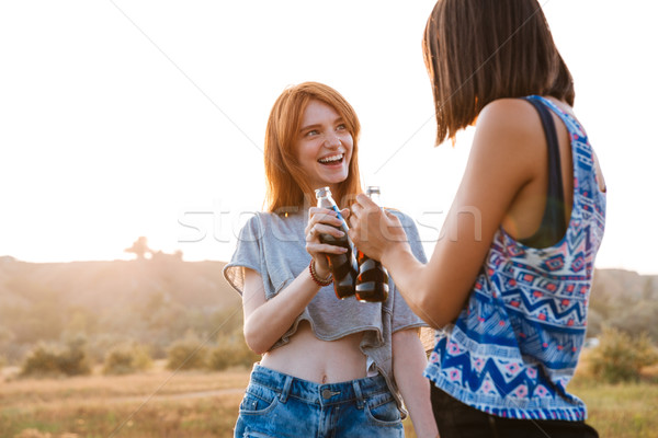 Zwei lächelnd junge Frauen trinken Soda Freien Stock foto © deandrobot
