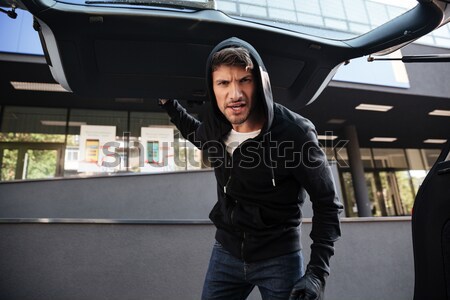 Criminal man threatening with gun and looking at car trunk Stock photo © deandrobot