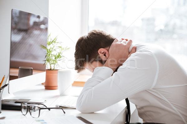 Tired young businessman with painful feelings holding neck. Stock photo © deandrobot