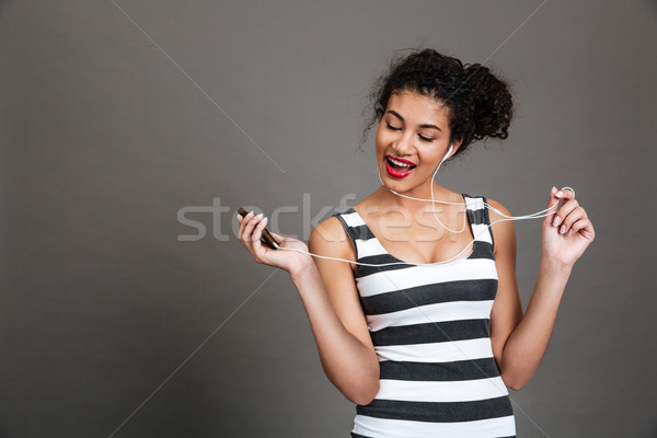 Young african american woman listening to music with earphones Stock photo © deandrobot