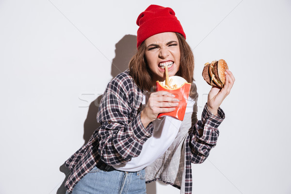 Hungry angry woman holding fries and burger Stock photo © deandrobot