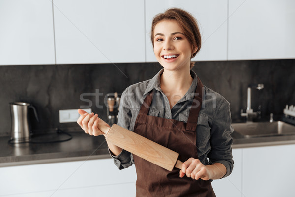 Beautiful woman standing in kitchen holding rolling pin Stock photo © deandrobot