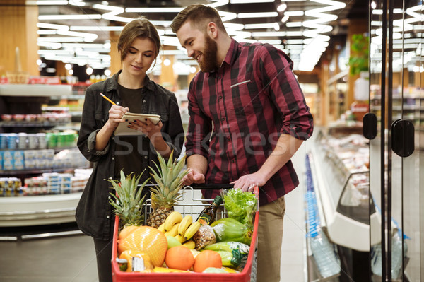 Cheerful loving couple in supermarket with shopping trolley Stock photo © deandrobot