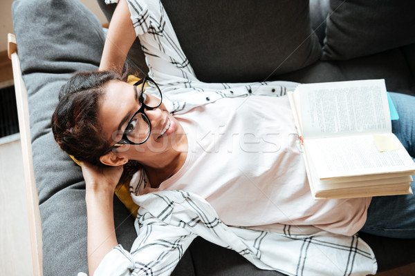 Happy african woman wearing glasses reading book. Stock photo © deandrobot