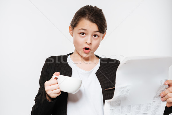 Confused young girl drinking coffee reading gazette Stock photo © deandrobot