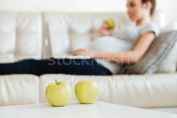 Apples on the table near pregnant young woman using laptop Stock photo © deandrobot