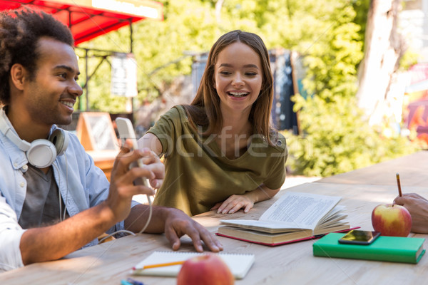 Surprised multiethnic friends looking at the display of mobile phone. Stock photo © deandrobot
