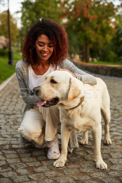 Young smiling lady in casual clothes sitting and hugging dog in park Stock photo © deandrobot