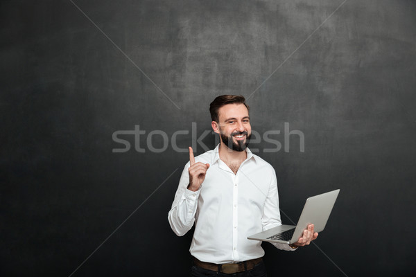 Picture of smart brunette man working in office using silver lap Stock photo © deandrobot