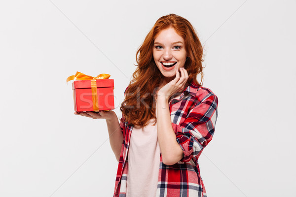 Image of Happy ginger woman in shirt holding gift box Stock photo © deandrobot