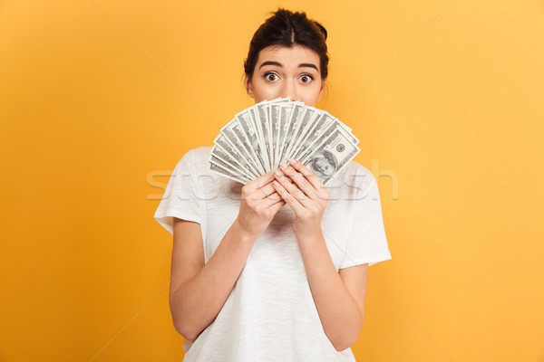Emotional young pretty woman holding money covering face. Stock photo © deandrobot