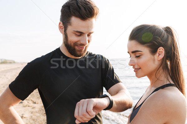 Joyful young sport couple looking at smartwatch Stock photo © deandrobot