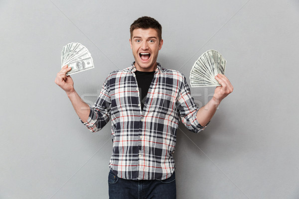 Portré izgatott fiatalember mutat pénz bankjegyek Stock fotó © deandrobot