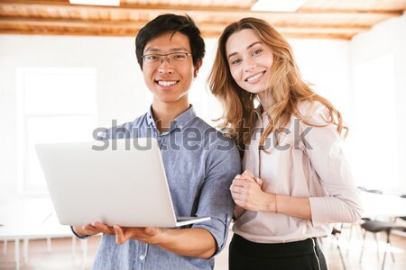 Sorridente negócio casal trabalhando computador portátil em pé Foto stock © deandrobot