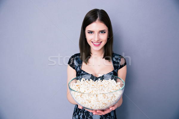 Happy young woman holding bowl of popcorn Stock photo © deandrobot