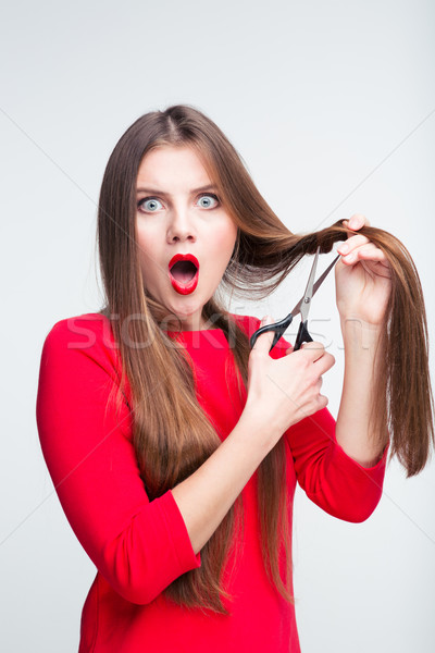 Portrait of a shocked woman cutting her hair Stock photo © deandrobot