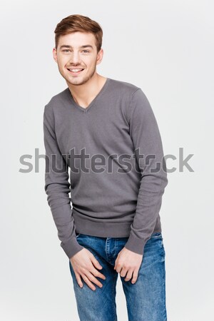Smiling attractive young man in grey pullover and jeans Stock photo © deandrobot