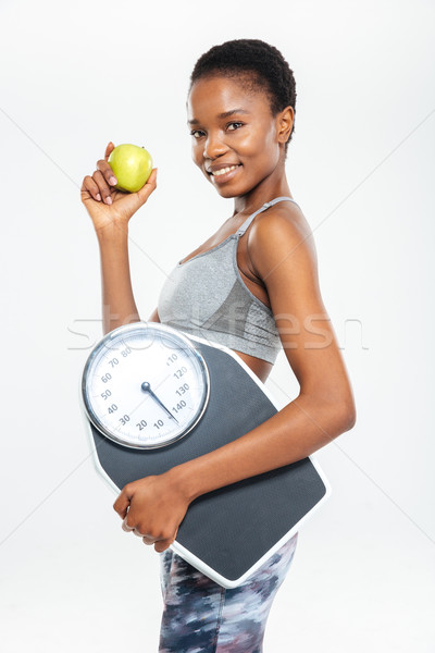 Happy afro american woman holding scales and apple Stock photo © deandrobot