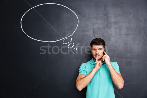 Man talking on cell phone and showing silence gesture Stock photo © deandrobot