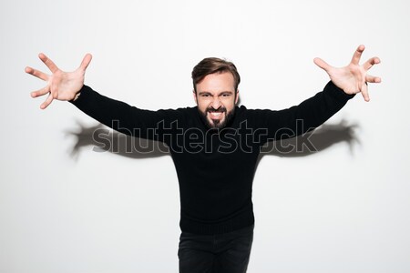 Stock photo: Scared young man holding gun and standing with hands up