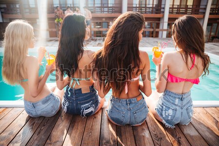Back view of cheerful young women talking near swimming pool Stock photo © deandrobot
