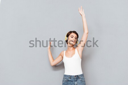 Mulher escuta música fones de ouvido as mãos levantadas para cima Foto stock © deandrobot
