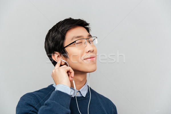 Asian man listening to music on headphones Stock photo © deandrobot