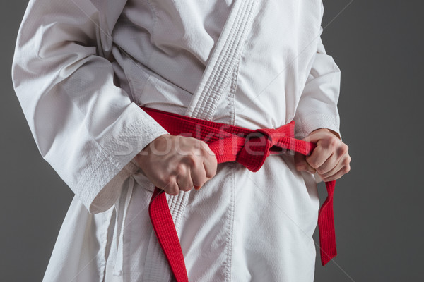Cropped image of sportsman dressed in kimono tightening red belt Stock photo © deandrobot