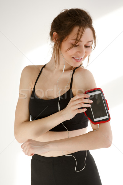 Cheerful sports woman listening music with earphones Stock photo © deandrobot