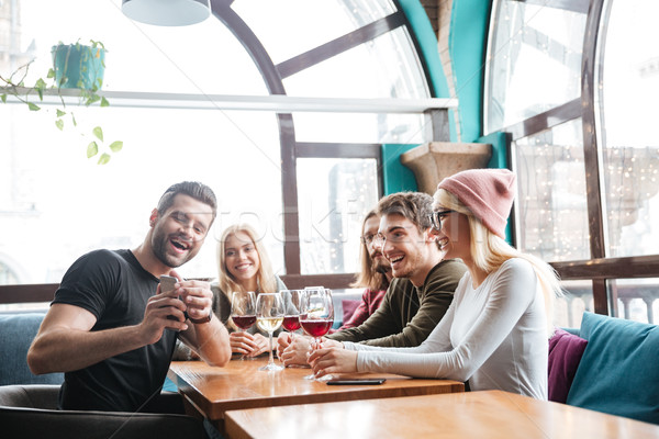 Smiling friends in cafe drinking alcohol and make a selfie. Stock photo © deandrobot