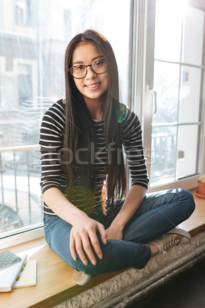 Vertical image of Asian woman on windowsill Stock photo © deandrobot